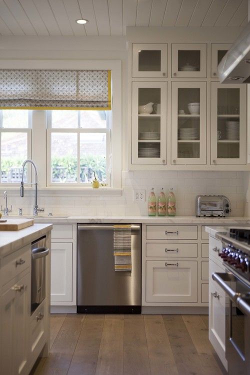Off white and glass insert cabinets with white paneling in the kitchen.