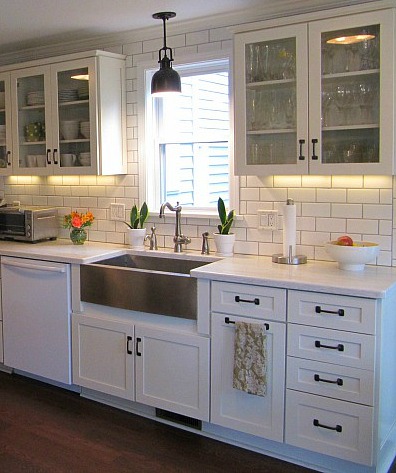 A white kitchen with glass cupboards and an apron style farmhouse sink.