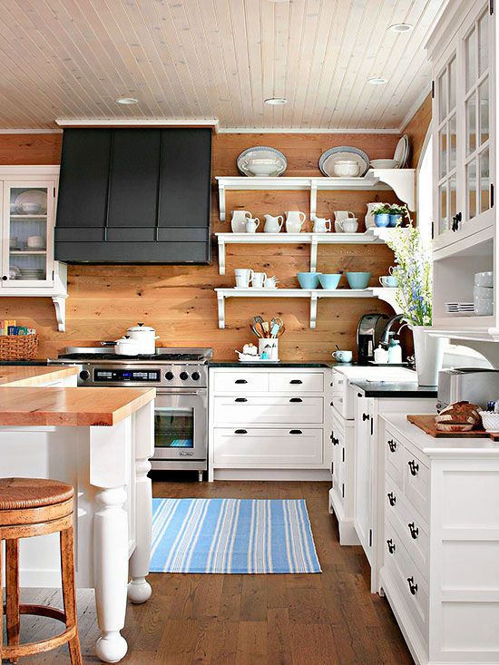 There is a wood kitchen with white shelves and white cabinets and a dark hood fan.