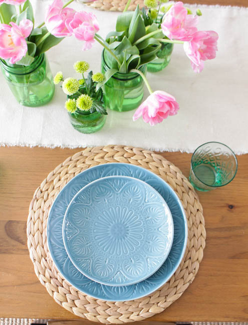 Light blue plates and pink and yellow flowers on the table.