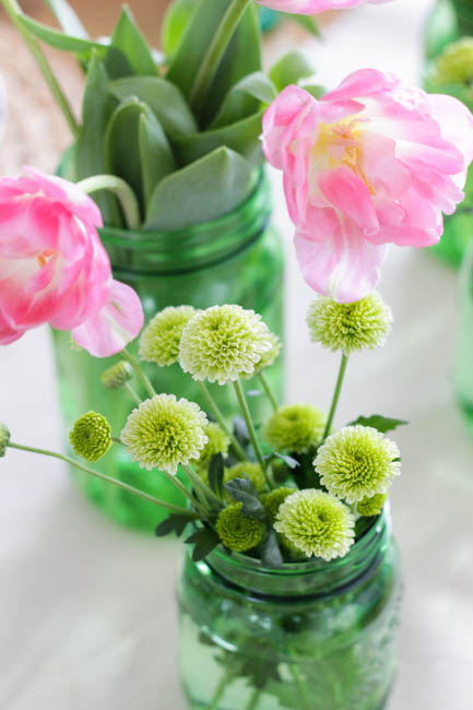 Green mason jars filled with flowers.