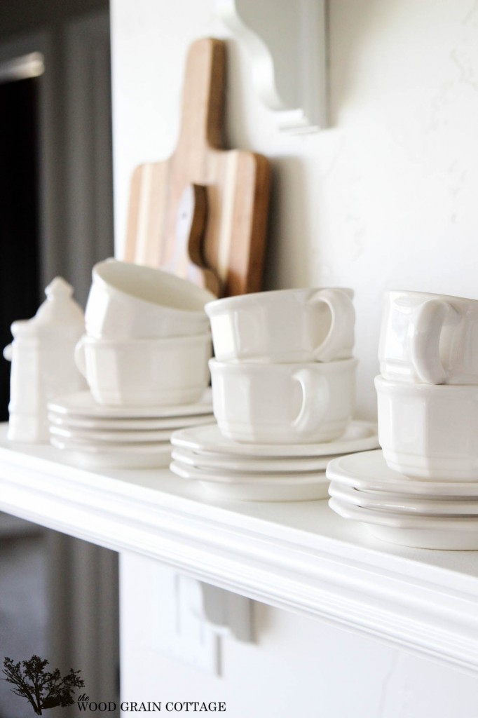 White tea cups and saucers on an open shelf.