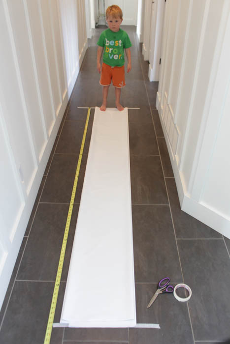 The liner for the drapes laid out on the floor in front of a little boy.