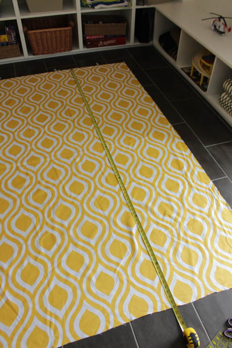 The yellow and white fabric for the drapes laid out on the floor.