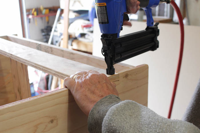Using an electric drill to screw the pieces into the wood.