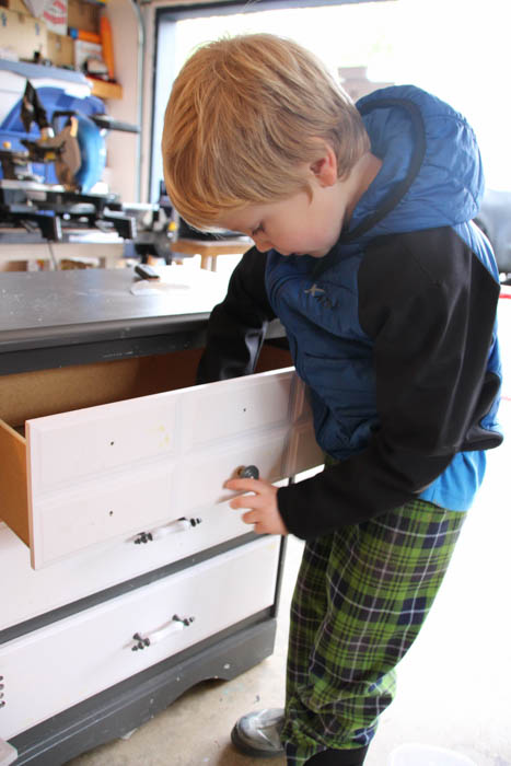 A little boy looking into the opened drawer.