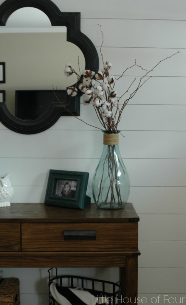 A white plank wall with a black mirror on it.