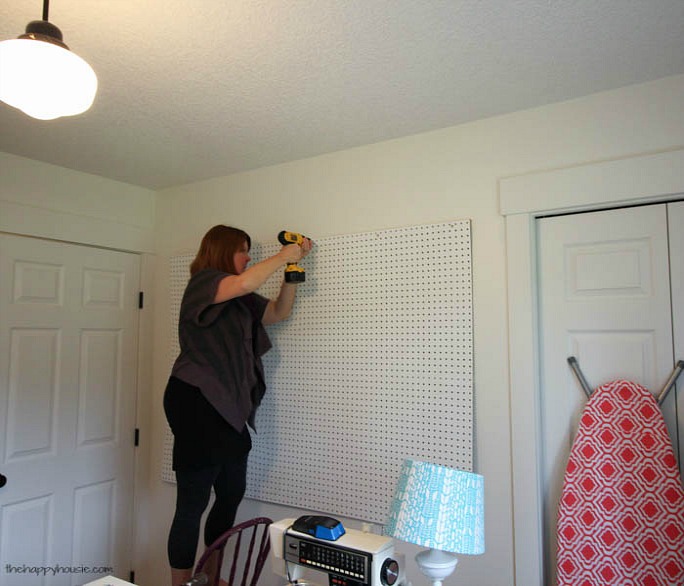 Krista hanging up the pegboard standing on a chair.