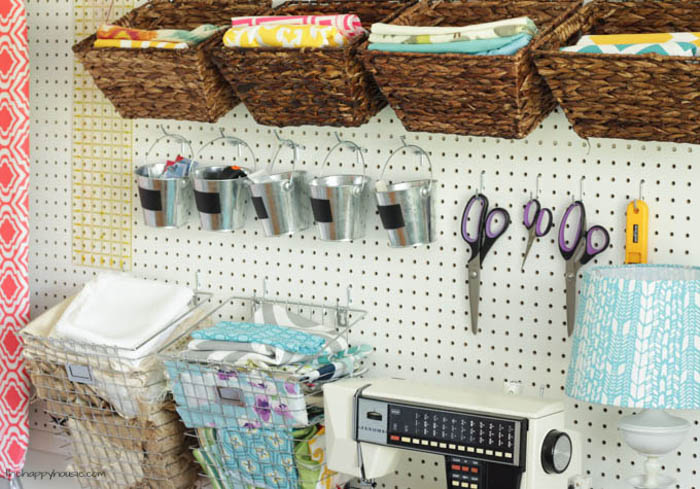 Wicker baskets hanging on the pegboard filled with fabric.