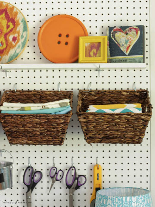 A shelf on the pegboard with a large decorative button and a frame with a picture.