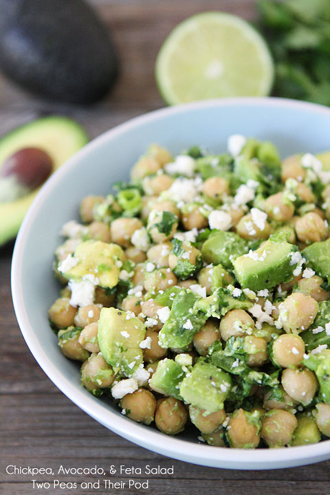 chickpea-avocado-and-feta-salad- in a bowl on the table beside a cut avocado and lime.