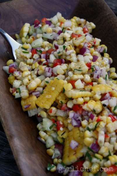 grilled corn salad with honey lime dressing in a wooden bowl with a fork in it.