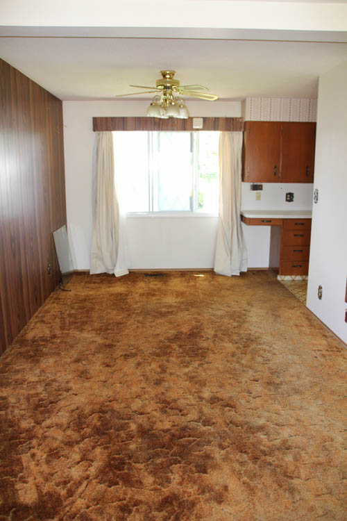 A small dining room with the dated carpet and dated ceiling fan.