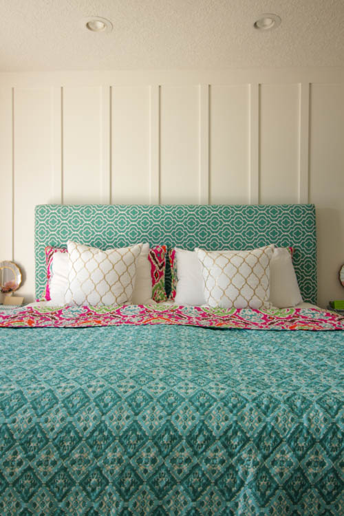 Brightly patterned bedspread in turquoise, gold and white pillows on the bed.