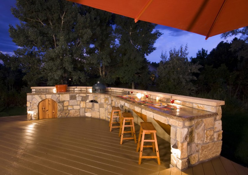 A stone island built into this deck with bar stools.