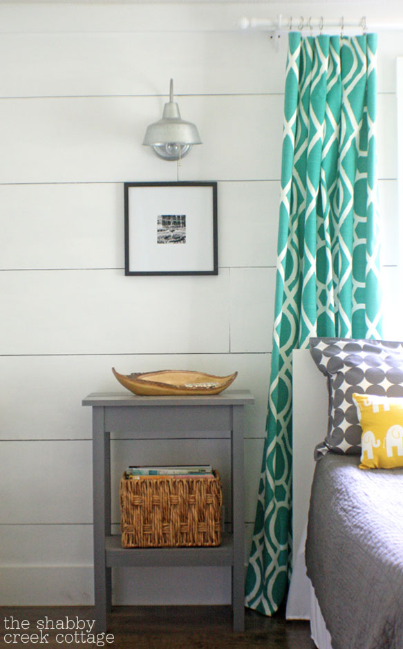 Plank walls with turquoise curtains.
