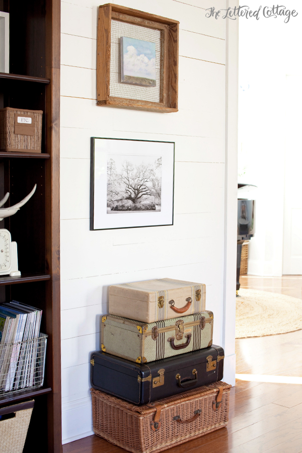 A white panelled wall with vintage suitcases stacked up underneath it.