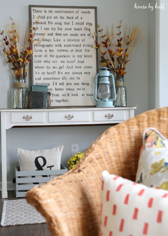 A fall side table decorated with foliage and a fall saying in a frame.