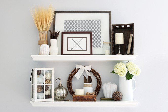 A white shelf decorated simply with fall decor items.