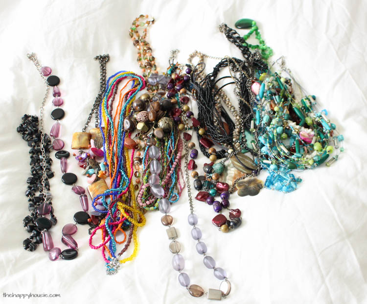 All the necklaces together in a bundle on the white bed spread.