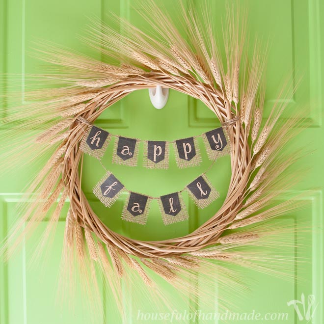 A wheat wreath hanging on a green front door.