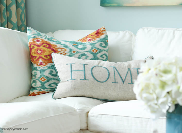 Turquoise, orange and white pillows on the couch.