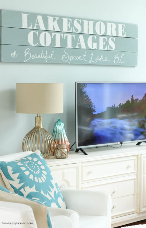 A sign that says lakeshore cottages is above the TV stand.