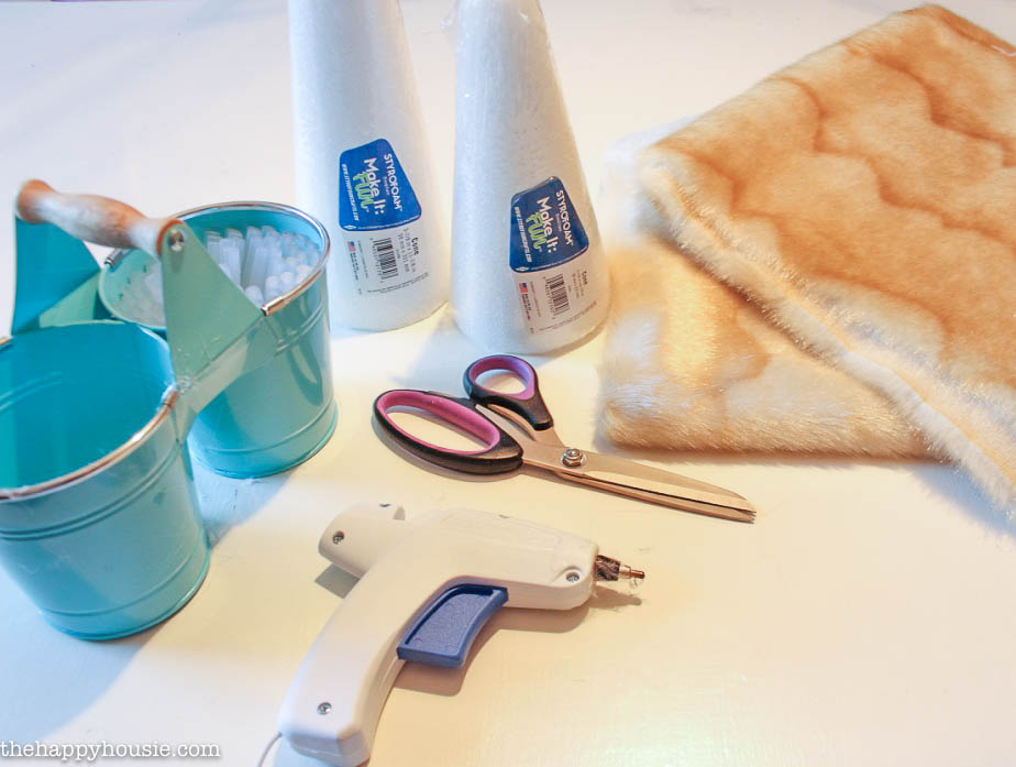Faux fur, glue, scissors and a hot glue gun on the table for the tutorial.