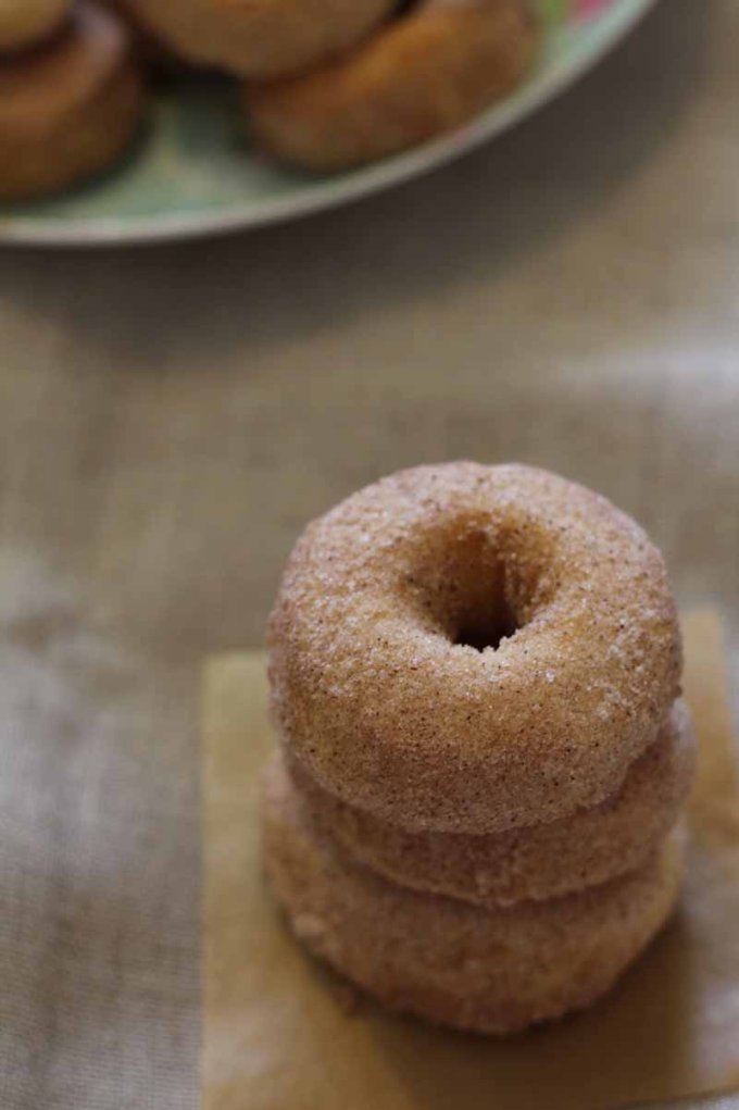 Cinnamon and sugar donuts stacked 3 high on the table.