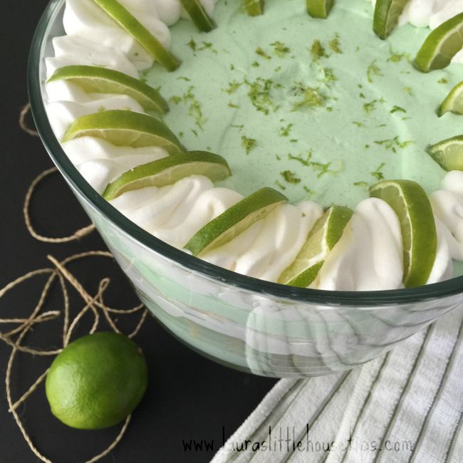 Key Lime Triffle in a large glass bowl with cut limes on top and a lime beside the bowl.