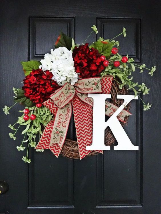 A dark front door with a red, white, and green wreath on it.