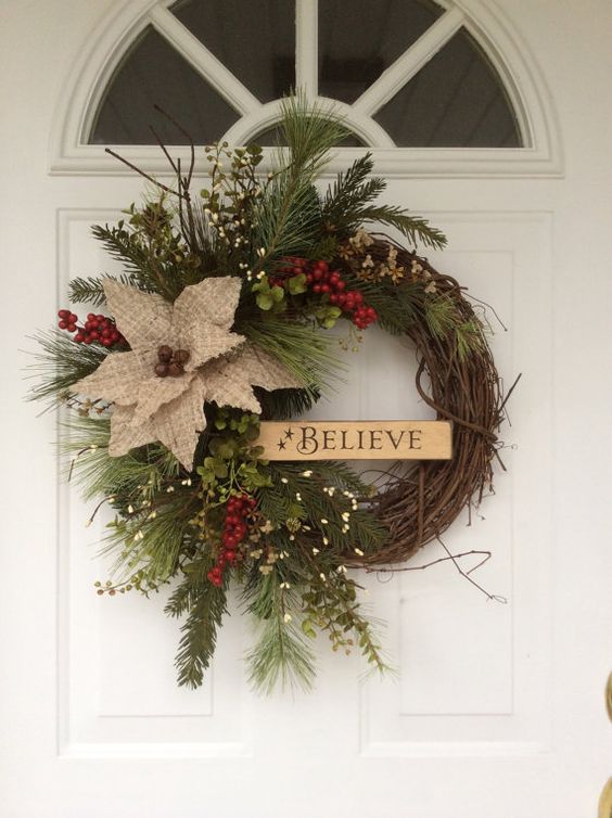 A grapevine wreath with holly and berries on a door.