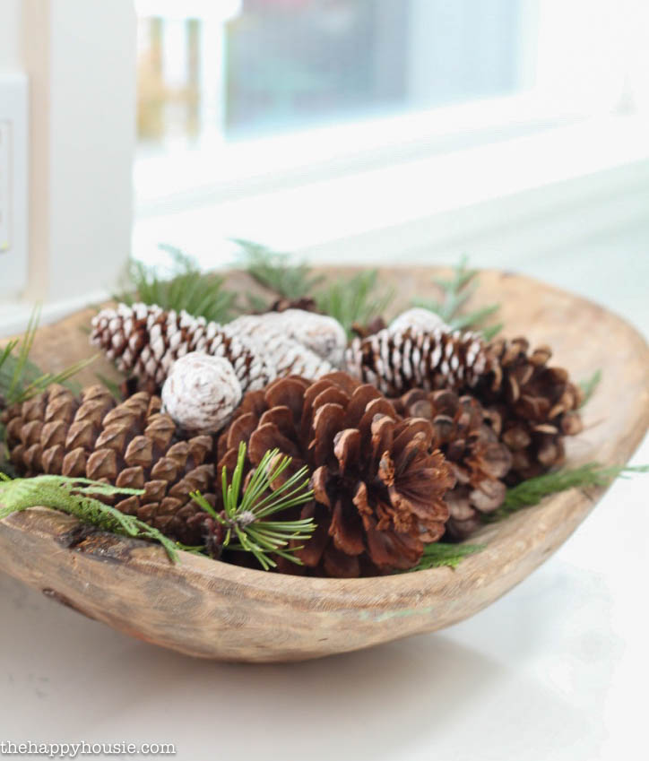 The wooden dough bowl filled with pine cones.
