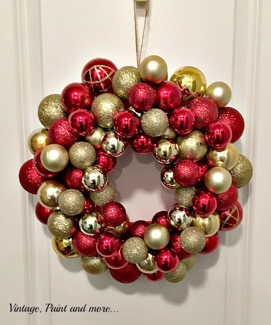 Gold and red Christmas balls in a circle making a wreath with a gold ribbon.