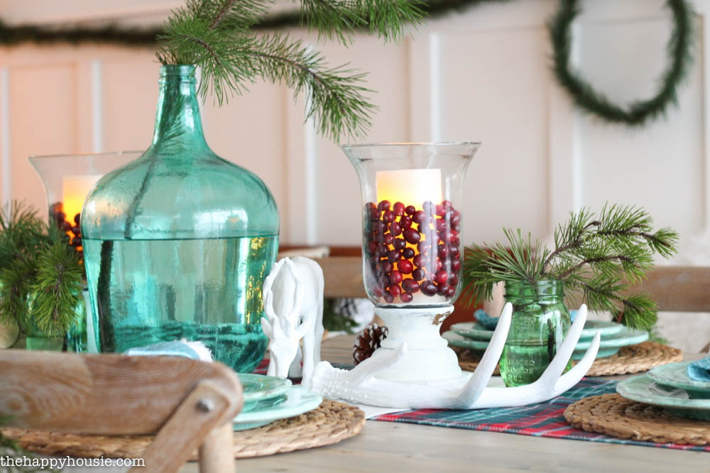 A glass candle holder with cranberries in it and a candle that is lit.