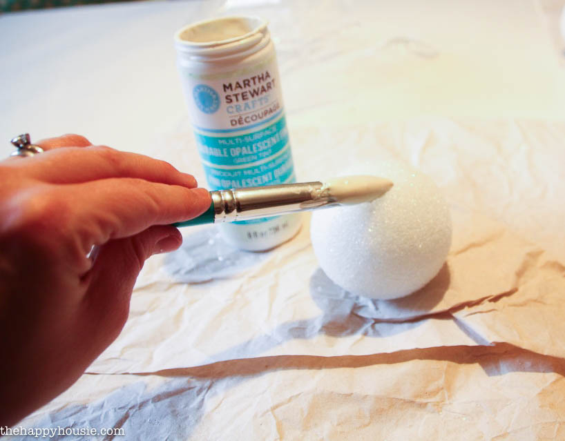 Applying decoupage to the styrofoam ball.