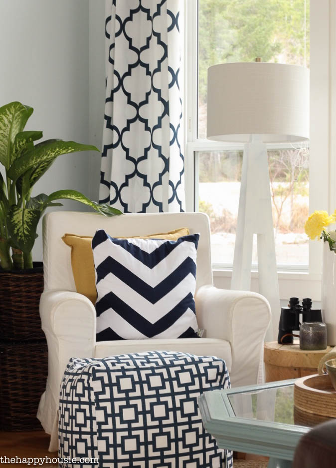 A large navy and white pouf is in front of the white chair.