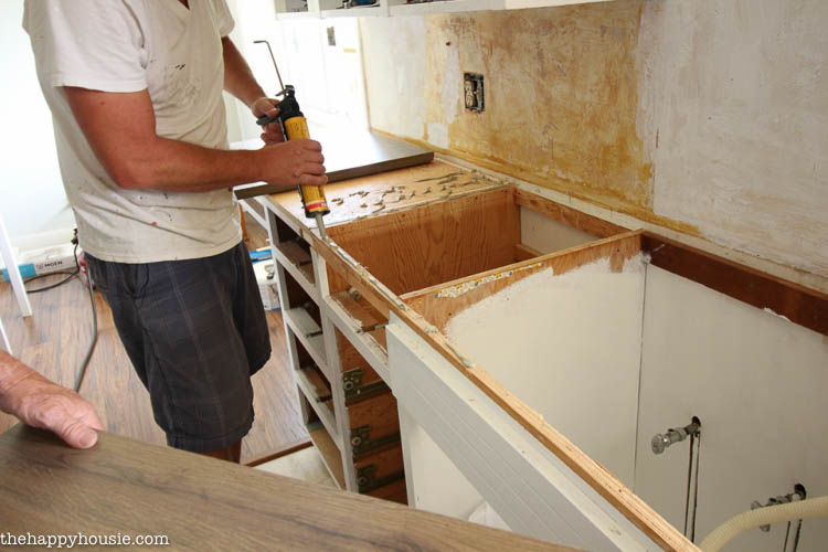 Using adhesive on the top of the wood structure before placing the new countertops.