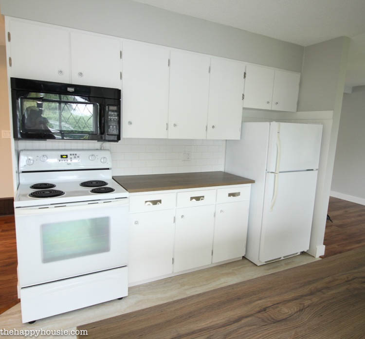 White kitchen cabinets, white stove, and a black microwave.