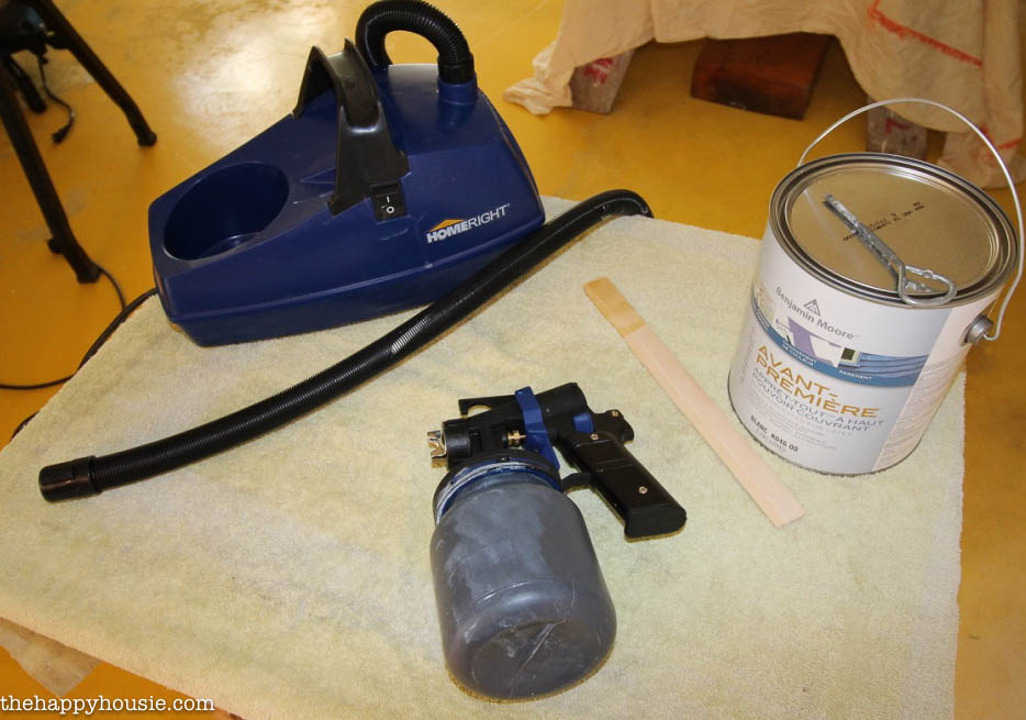 A paint sprayer device with a can of paint beside it.