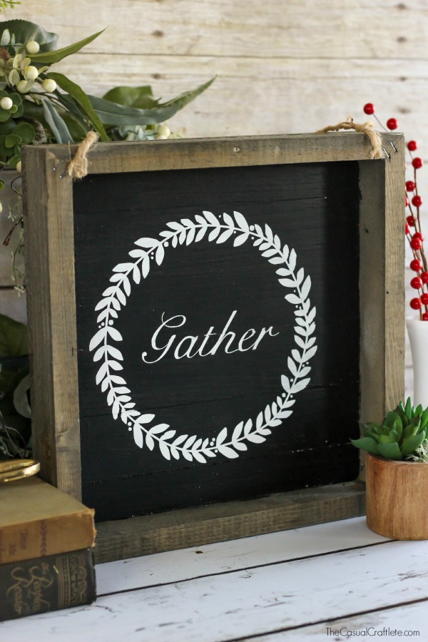 A black and white sign with the word gather written in white on wood painted black.