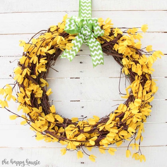Bright yellow forsythia wreath with a green and white bow.