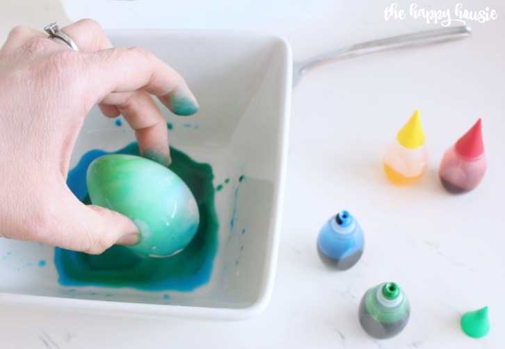 Dipping the same egg into green dye.