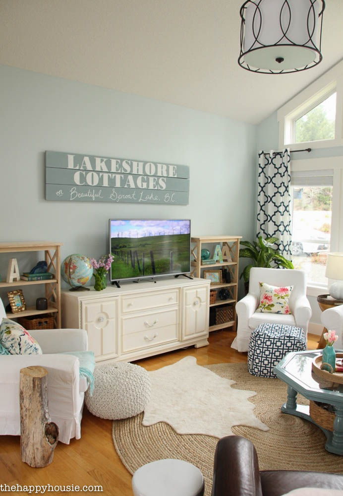 A living room with a wooden painted sign that says Lakeshore Cottages on it.