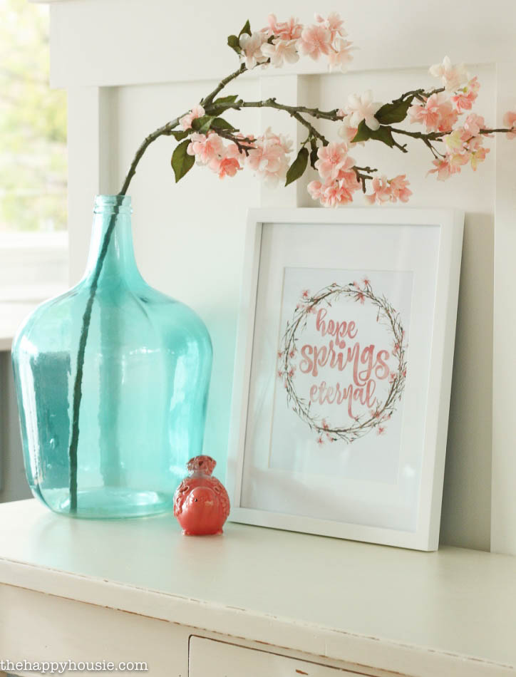 A vase of flowers beside the printable on the console table.