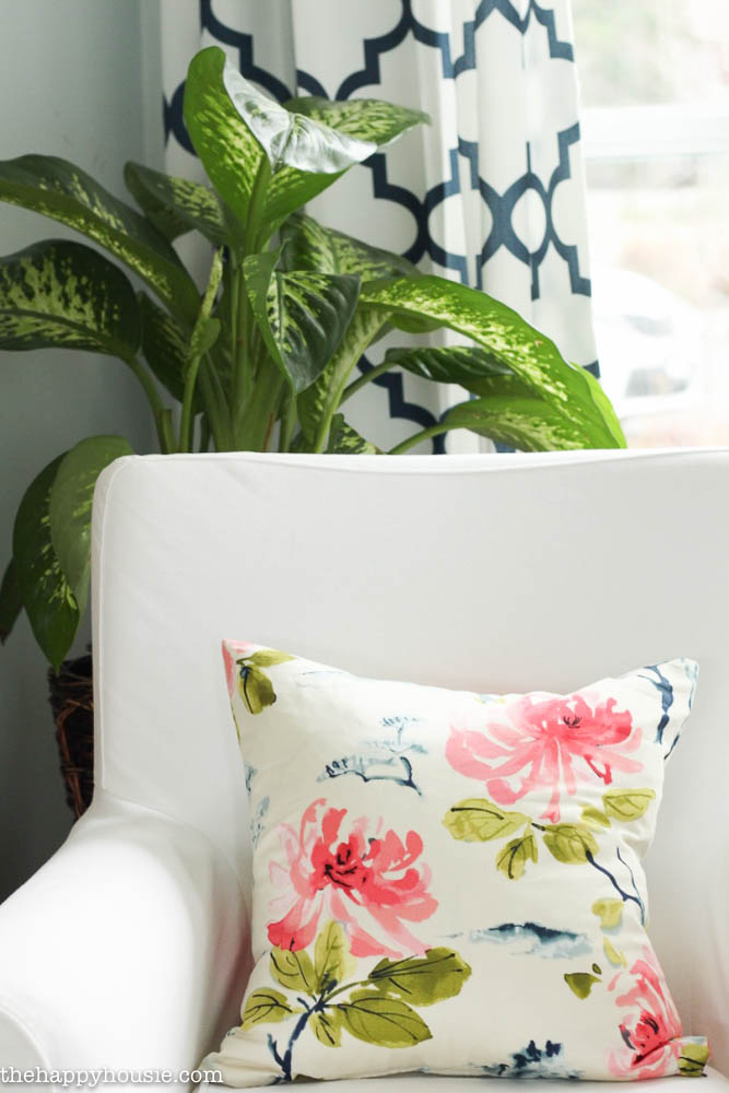 A spring inspired pillow is on the armchair in the living room.