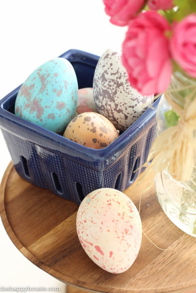 A small blue dish is filled with decorated Easter eggs.