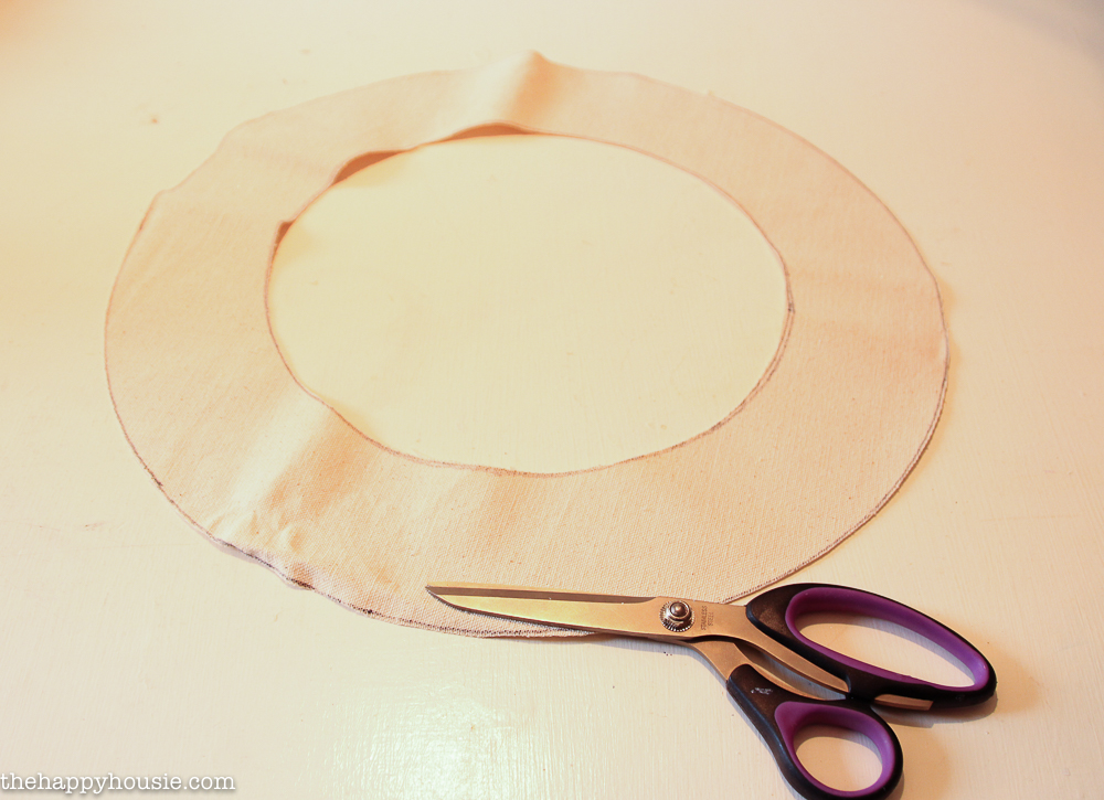 Cutting a piece of cloth into a circle to fit the wreath.