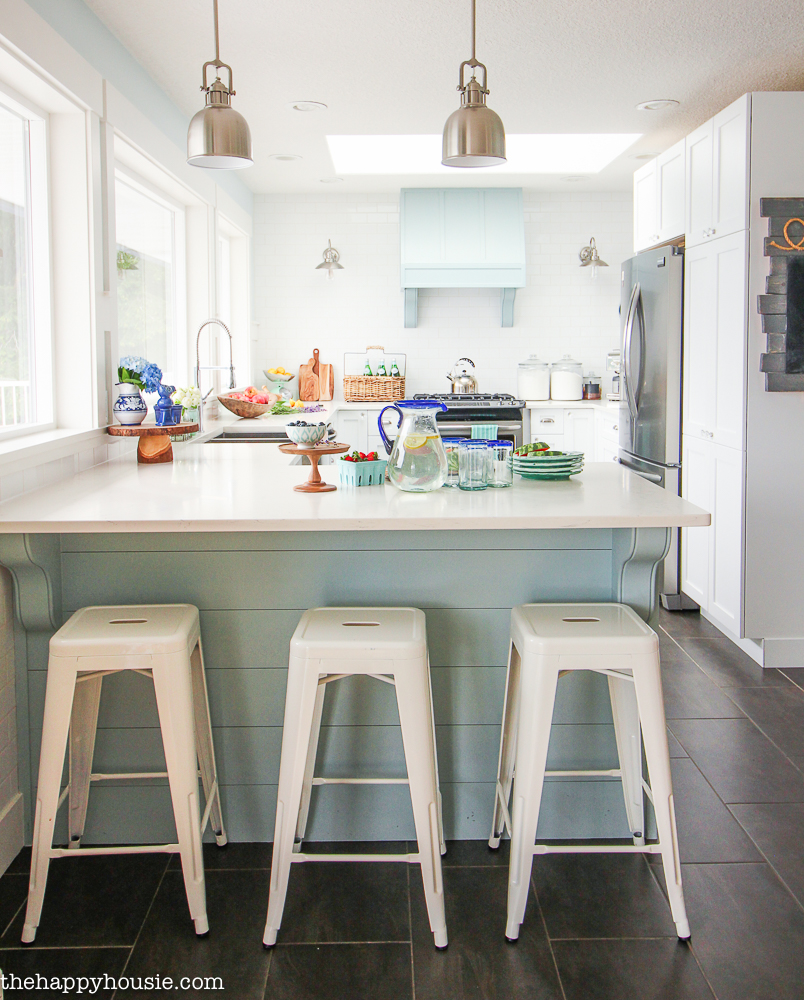 A light blue kitchen island with three stools underneath it.