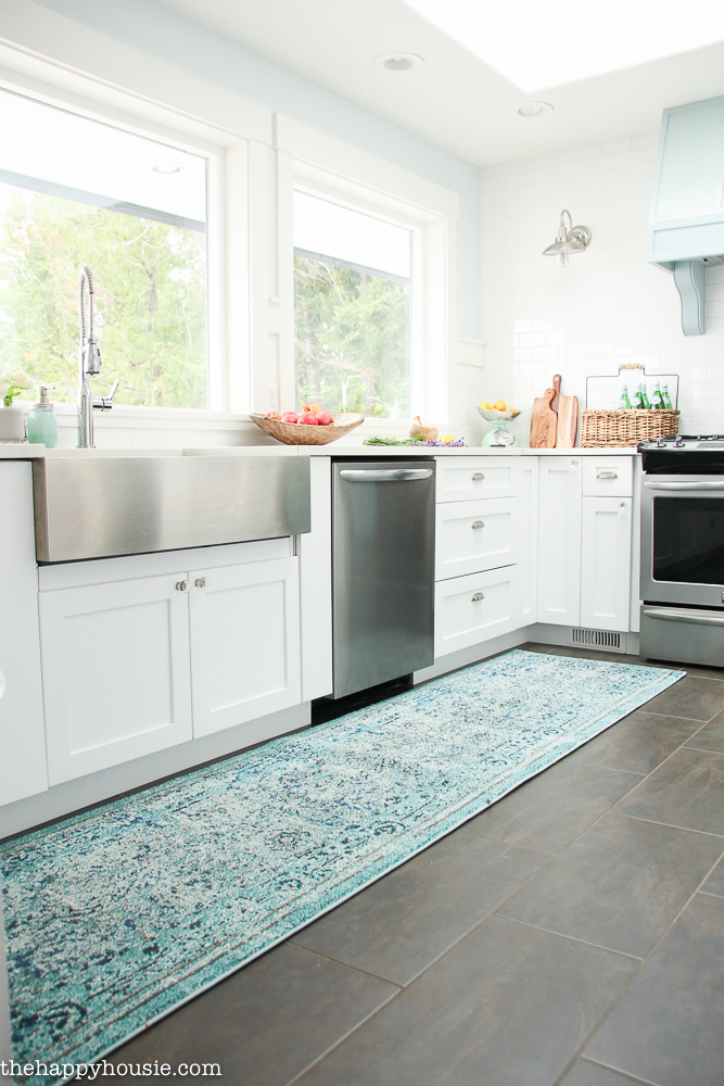 The all white and stainless steel kitchen with a runner rug in shades of blue and green.